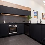 A photo of a kitchen with an oven, dishwasher, a plant on the counter and a sink.