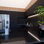 A photo of a kitchen counter with a plant, a sink, stove and a fridge.