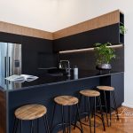 A photo of a kitchen with four chairs and a fridge.