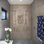 A photo of two shower heads with blue towels hanging on a towel rack on the wall.