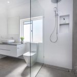 A photo of a bathroom with a view from the shower, with a toilet a sink and a towel rack.