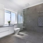 A photo of a bathroom with a cabinet with a sink on it, a toilet and a shower with a towel rack.