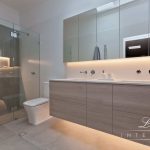 A photo of a bathroom area, with a shower, toilet and dual sinks.