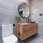 A photo of a sink, with a large round mirror in the background.