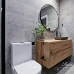 A photo of a sink, with a large round mirror in the background.