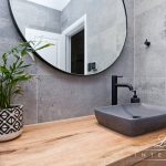 A photo of a sink, with a large round mirror in the background.