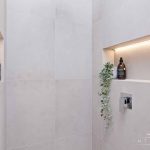 A photo of a bathroom shower, with various soaps and plants.