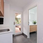 A photo of a laundry and bathroom with a door in the background.