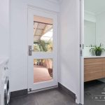 A photo of a laundry and bathroom with a door in the background.