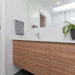 A photo of a bathroom sink, with a large mirror and succulent plant.