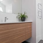 A photo of a bathroom area with a succulent on the sink bench top.