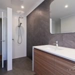 A photo of a shower area with dual sinks next to it.