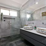 A photo of a bathroom with dual sinks and a shower in the background.