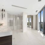 A photo of an ensuite bathroom, all white marble, with views of the swan river in the background.