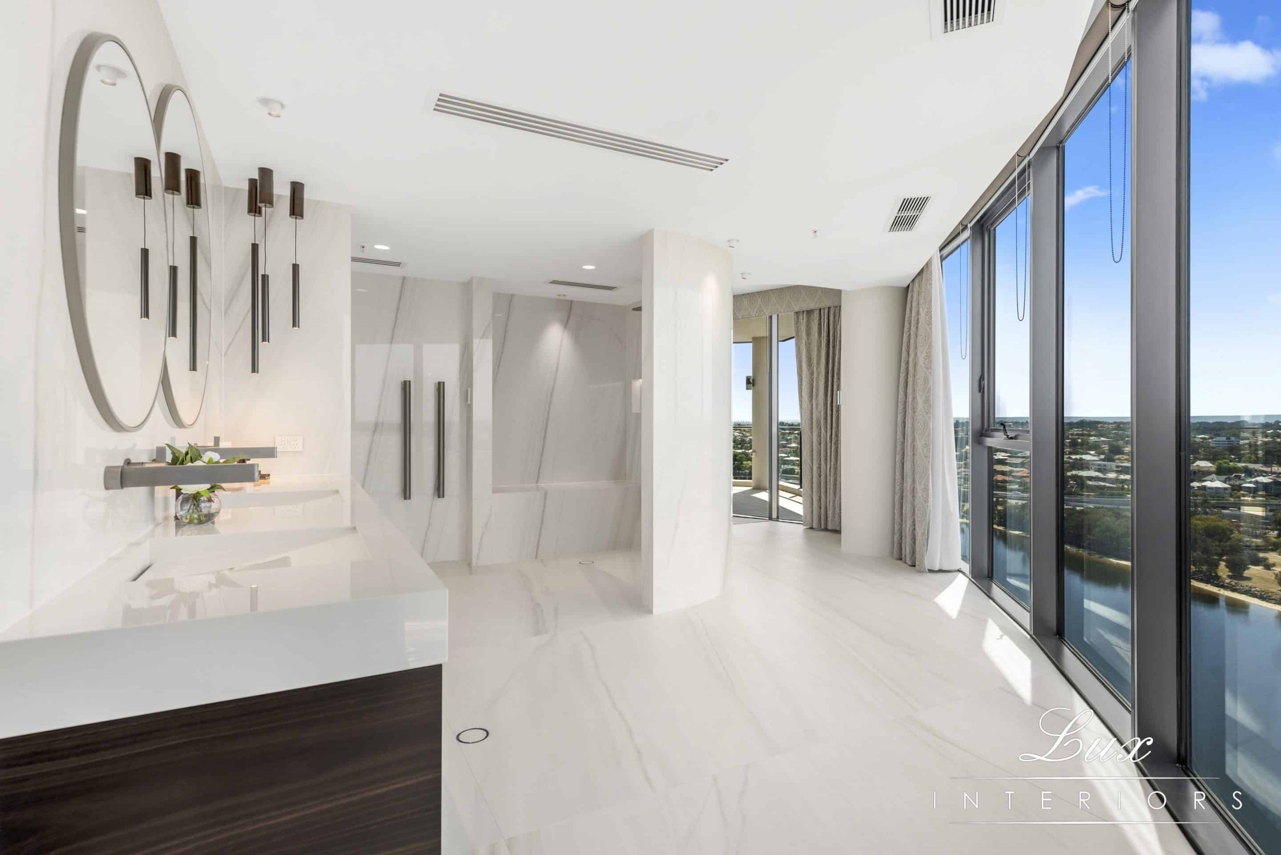 A photo of an ensuite bathroom, all white marble, with views of the swan river in the background.