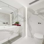 A photo of a sink, with a large mirror. There is a toilet next to the sink.