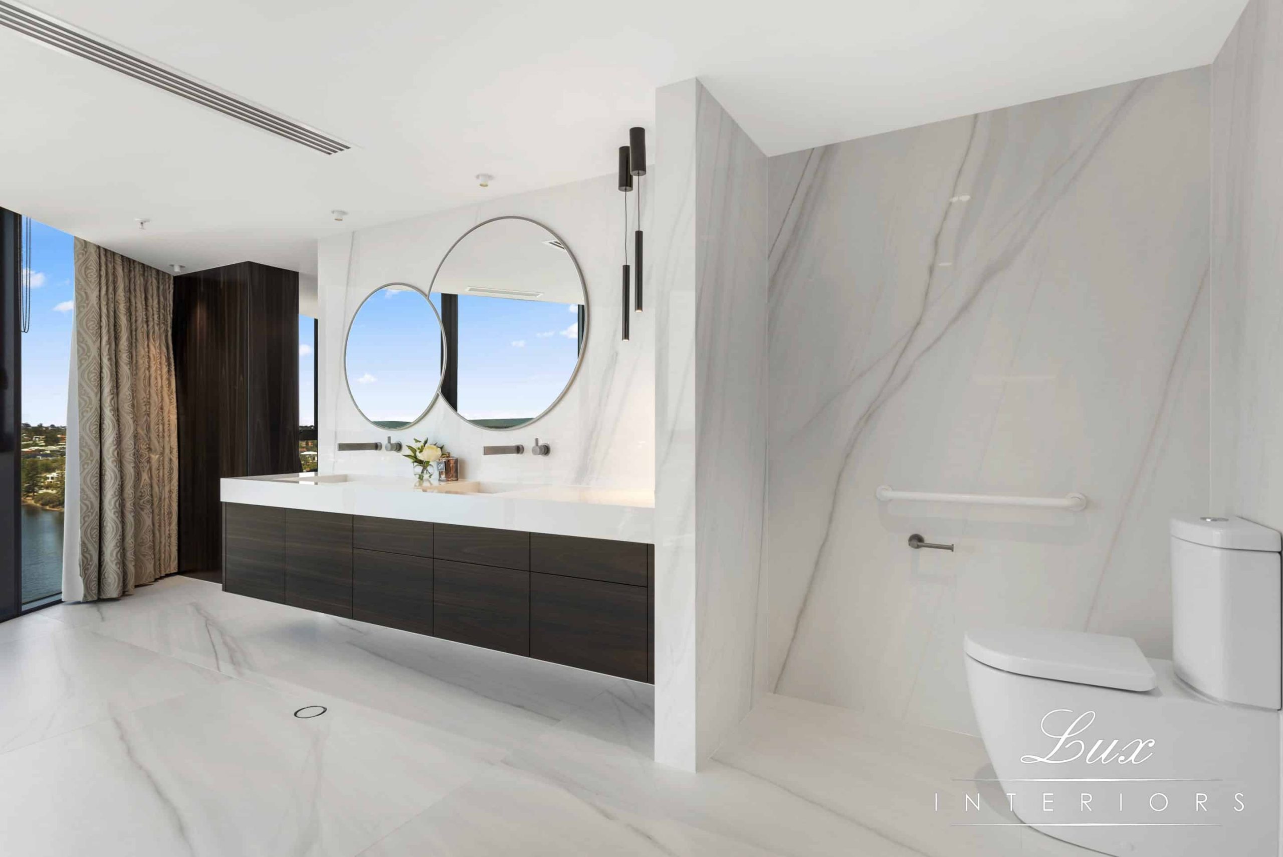 A photo of an ensuite bathroom area, with a toilet and dual sinks. The swan river is visible in the background.