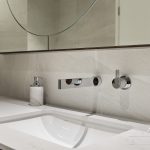 A photo of a large sink area, with a rectangular tap and large mirror.