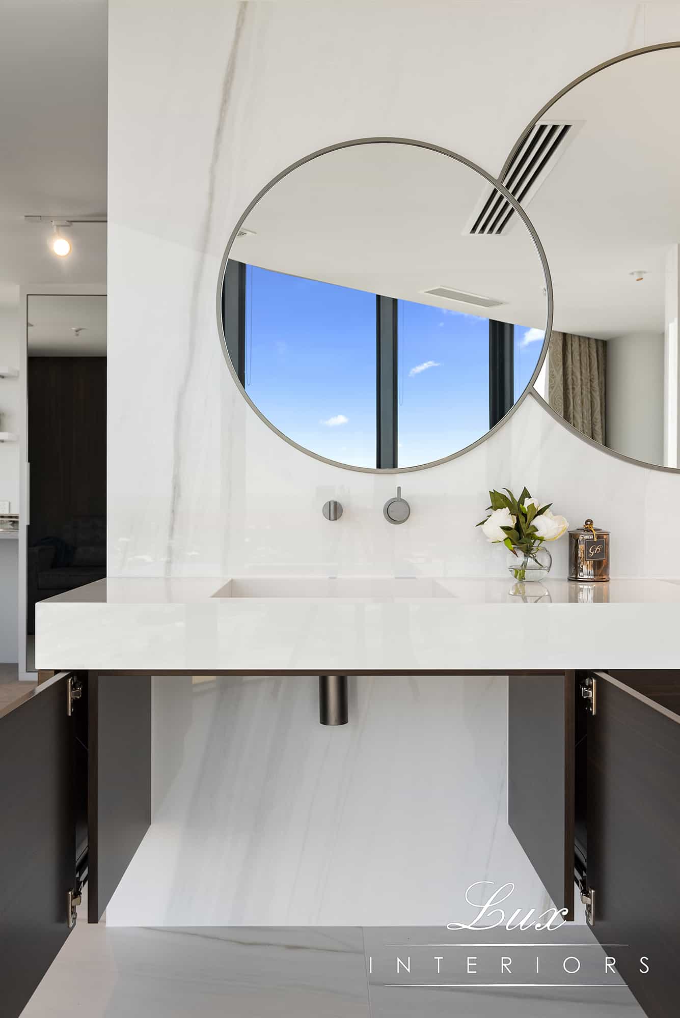 A photo of a sink, with large circular mirrors behind it.