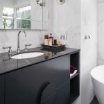 A photo of a sink area, with a large bath tub in the background.