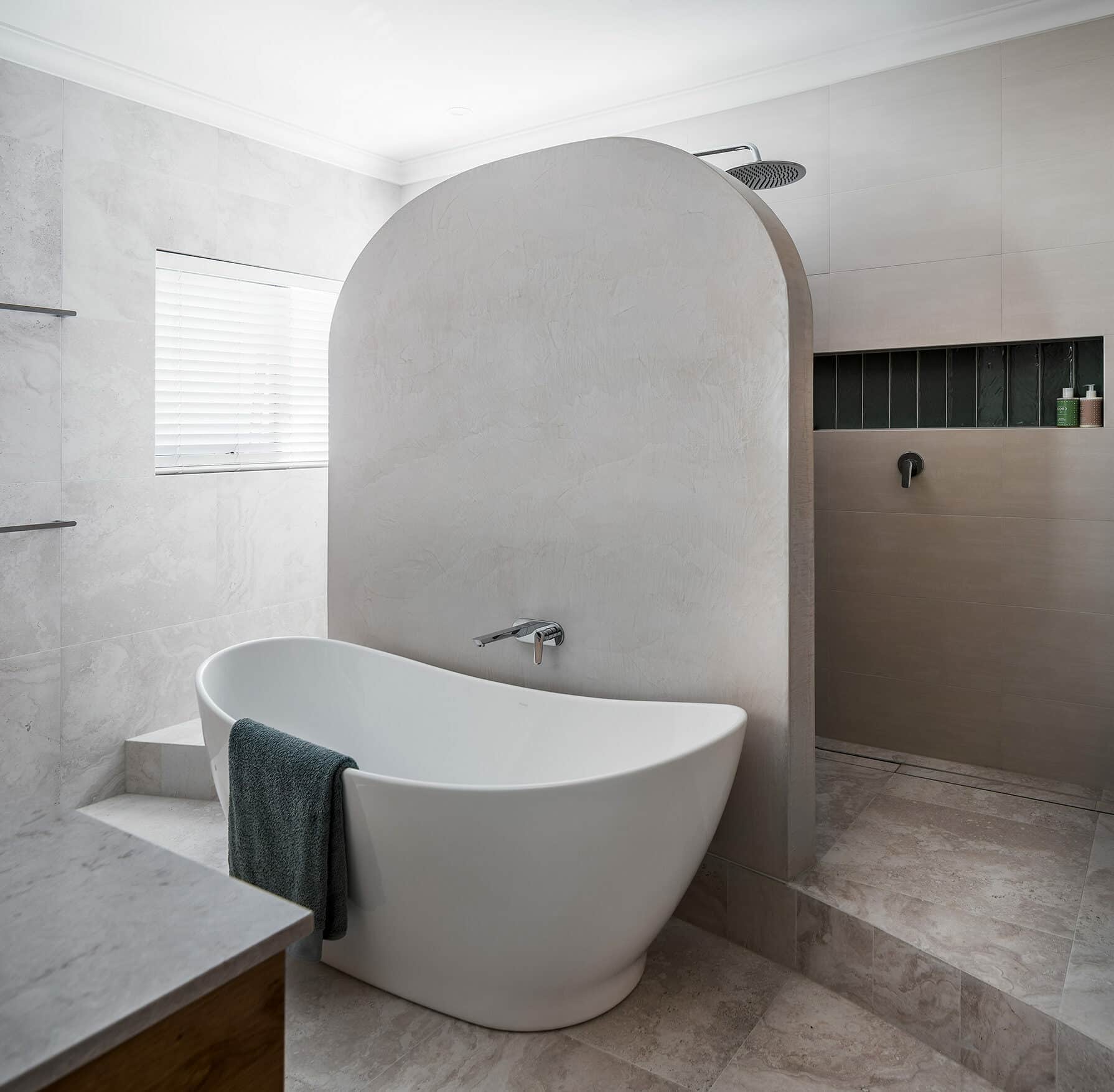 A photo of a curved dividing wall in a bathroom, in front of a bath tub.