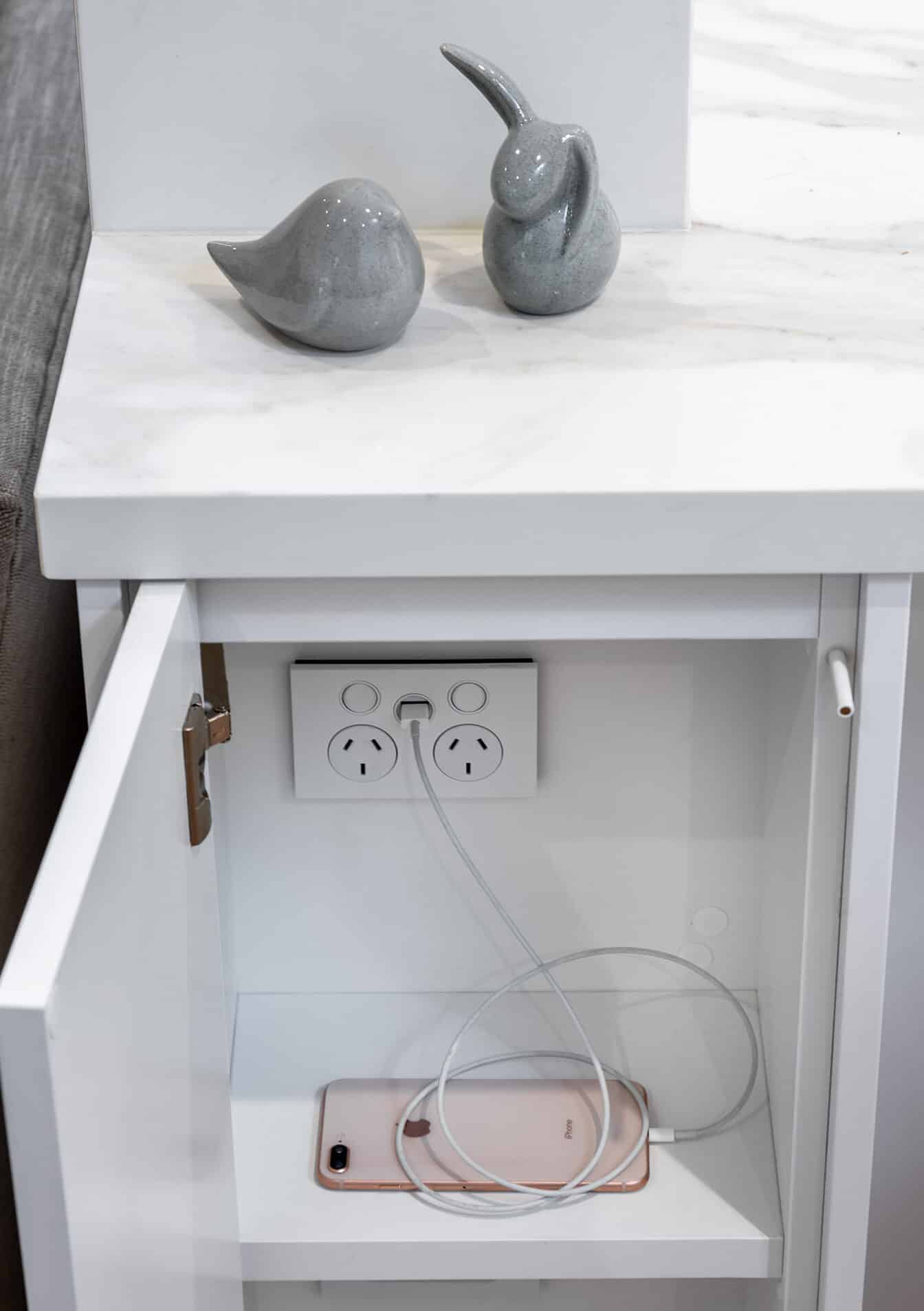 A photo of some hidden charging stations, with a ceramic dove and rabbit sitting on the bench top for decorations.