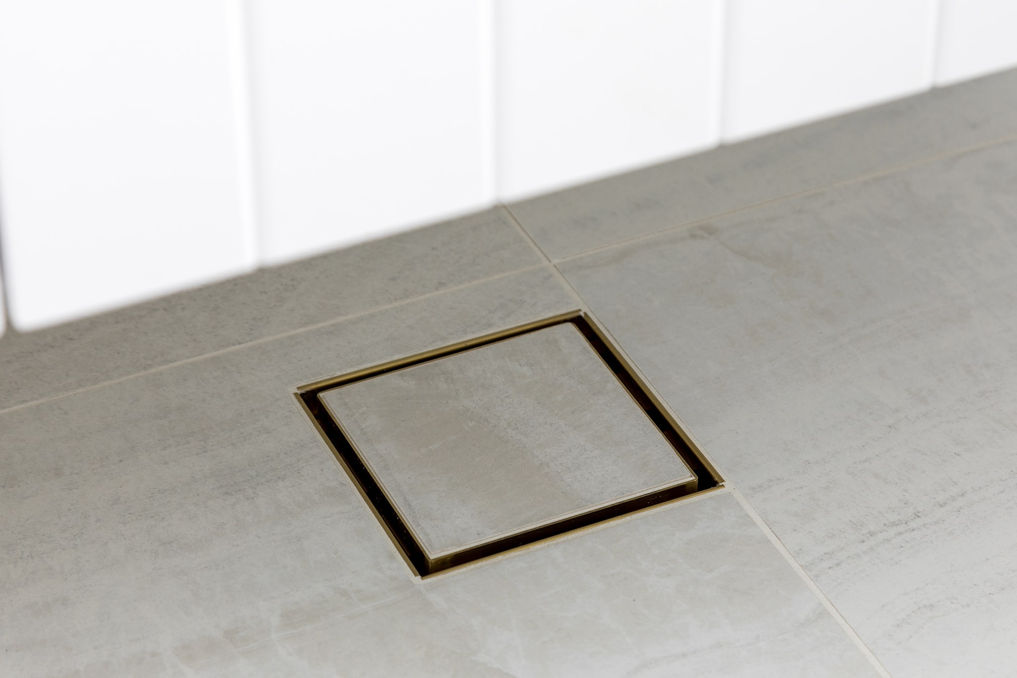 A photo of a square drain in the shower.