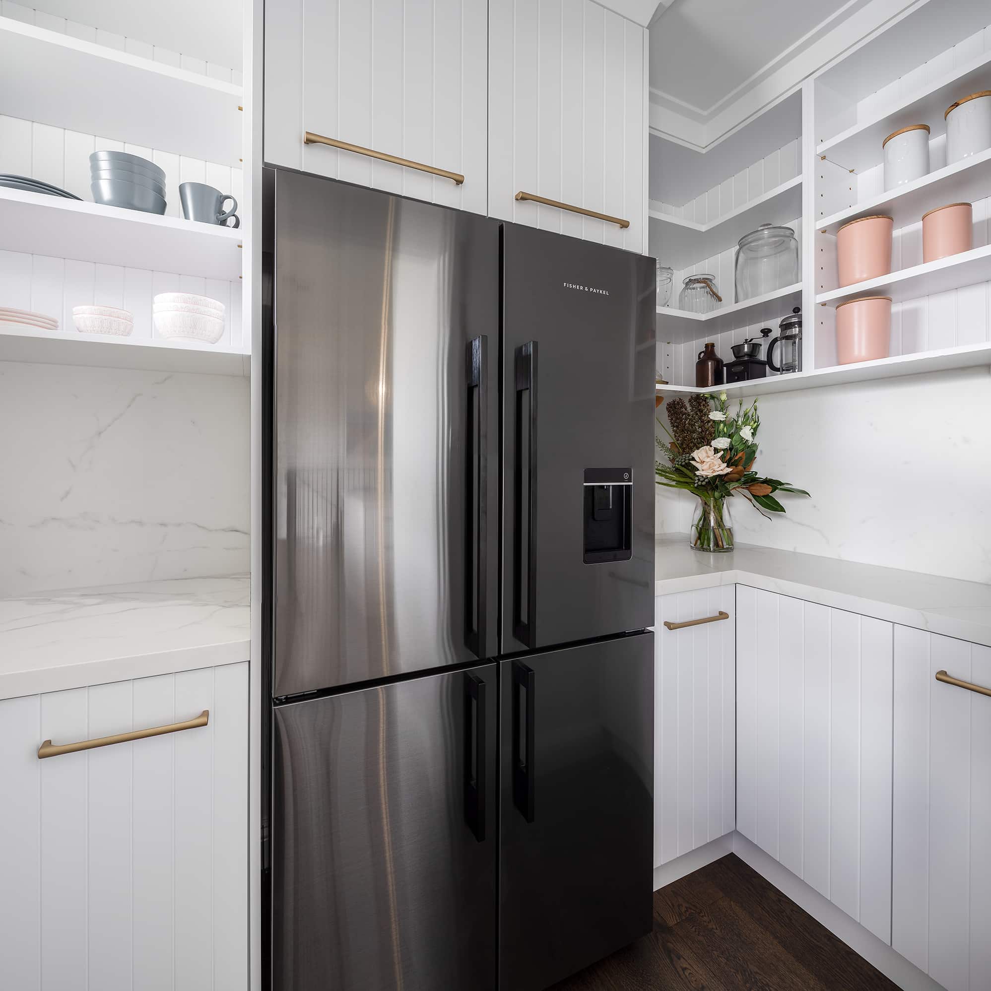 A photo of a large, black fridge in the kitchen next to cabinets.