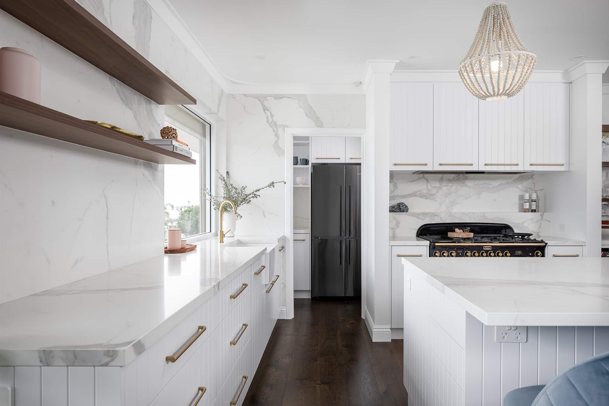 A photo of a kitchen area with counters to the sides and a pantry near a fridge in the background.