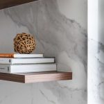 A photo of some books and decorations next to a marble wall.