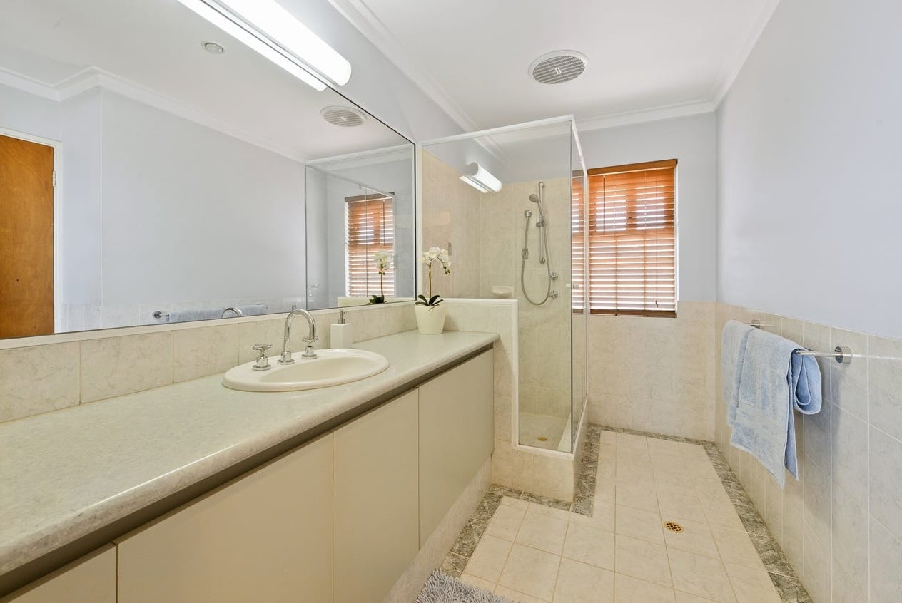 A photo of a bathroom before being renovated with a blue towel on the rack,