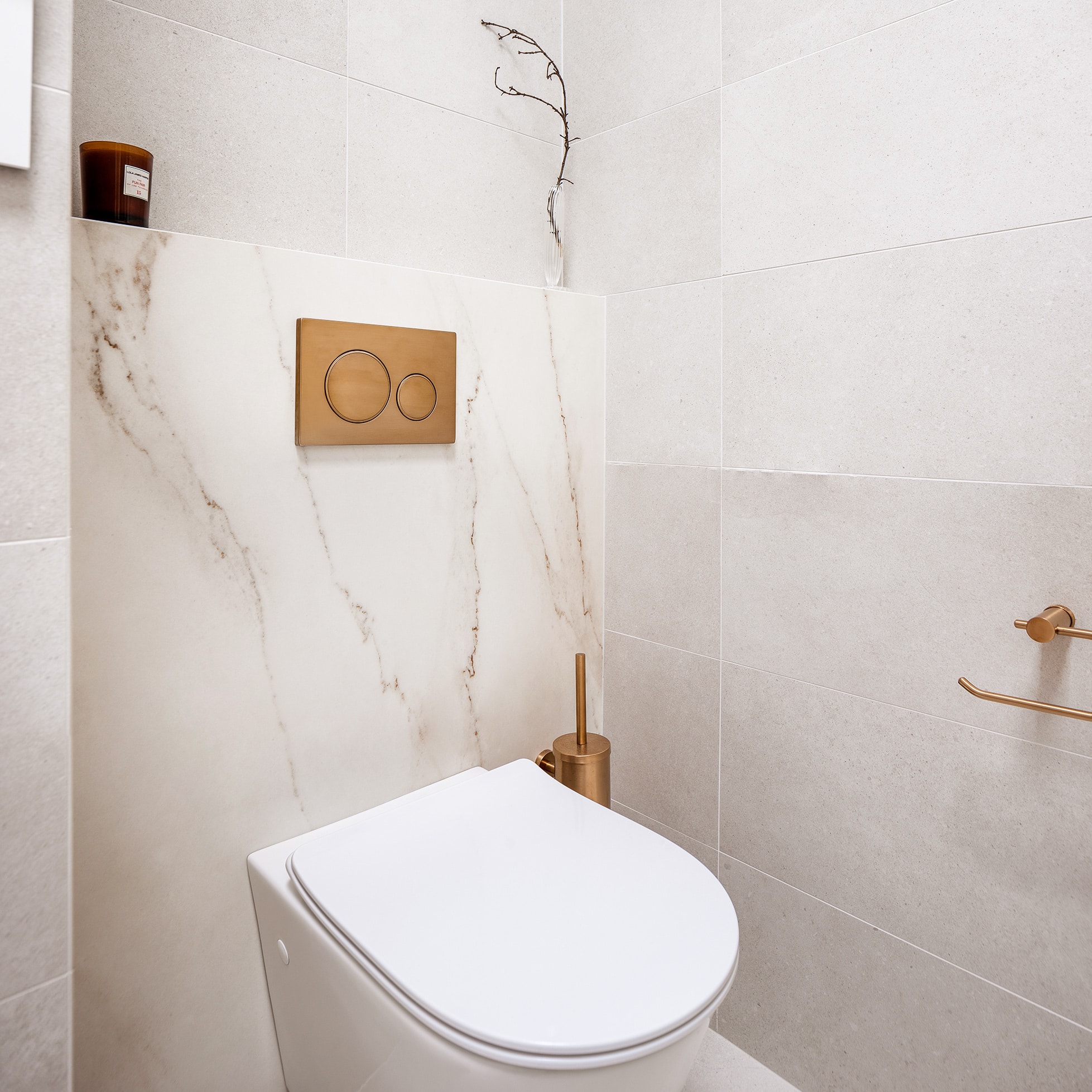 A photo of a toilet, with gold toilet roll holder.