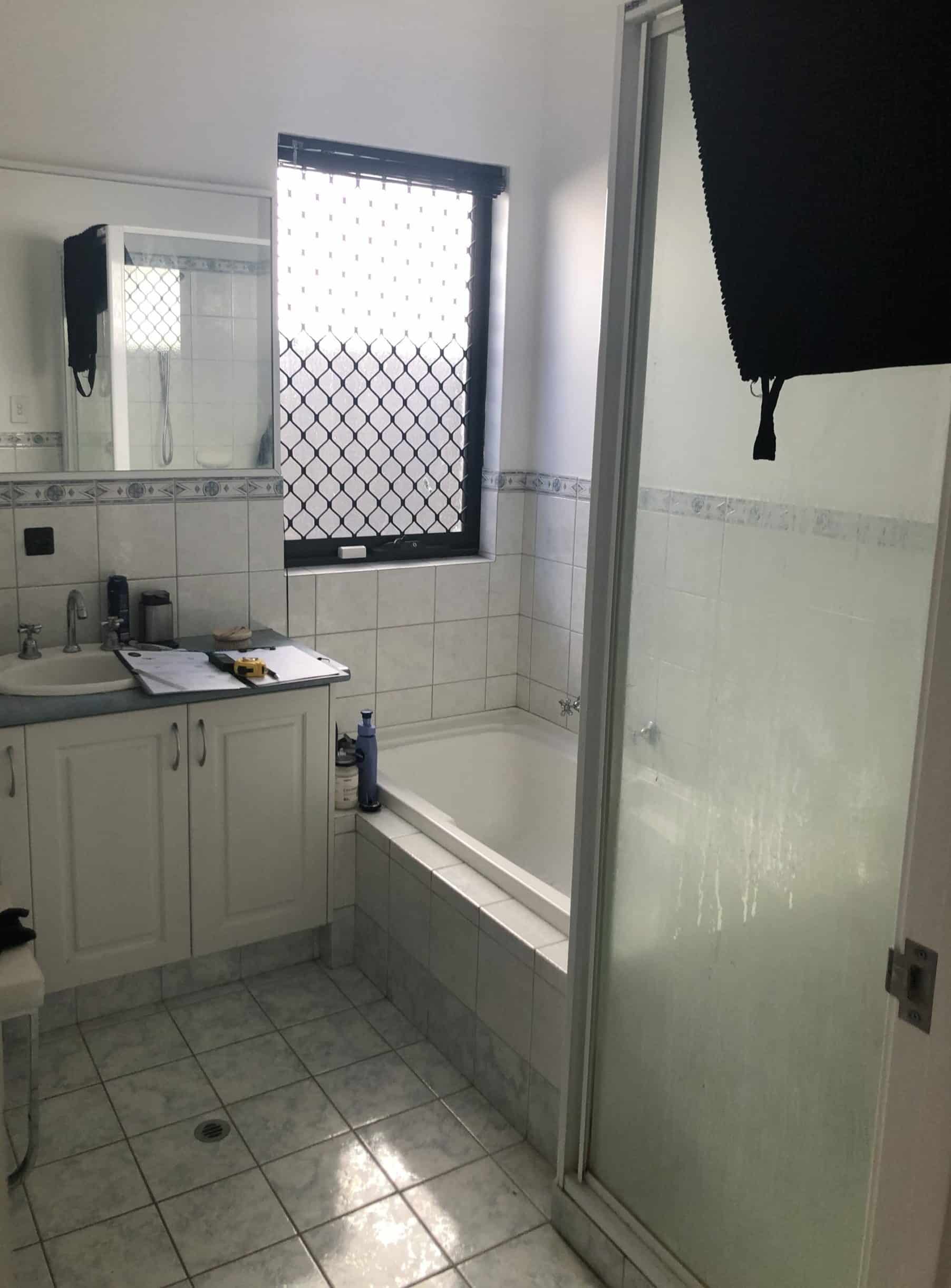 A photo of a bathroom, old and out-dated, with a sink, bath and shower.