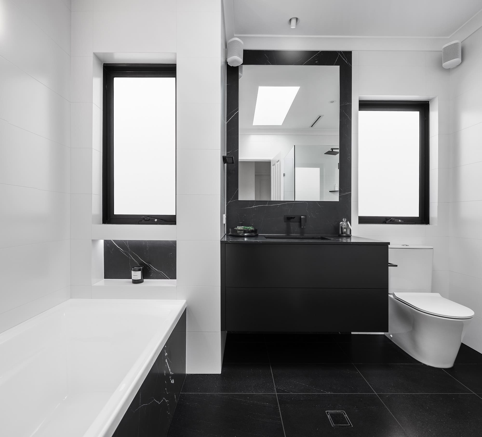 A photo of a freshly renovated bathroom, with a bath, sink and toilet.