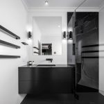 A photo of a freshly renovated bathroom, all black and white, with a shower and sink.