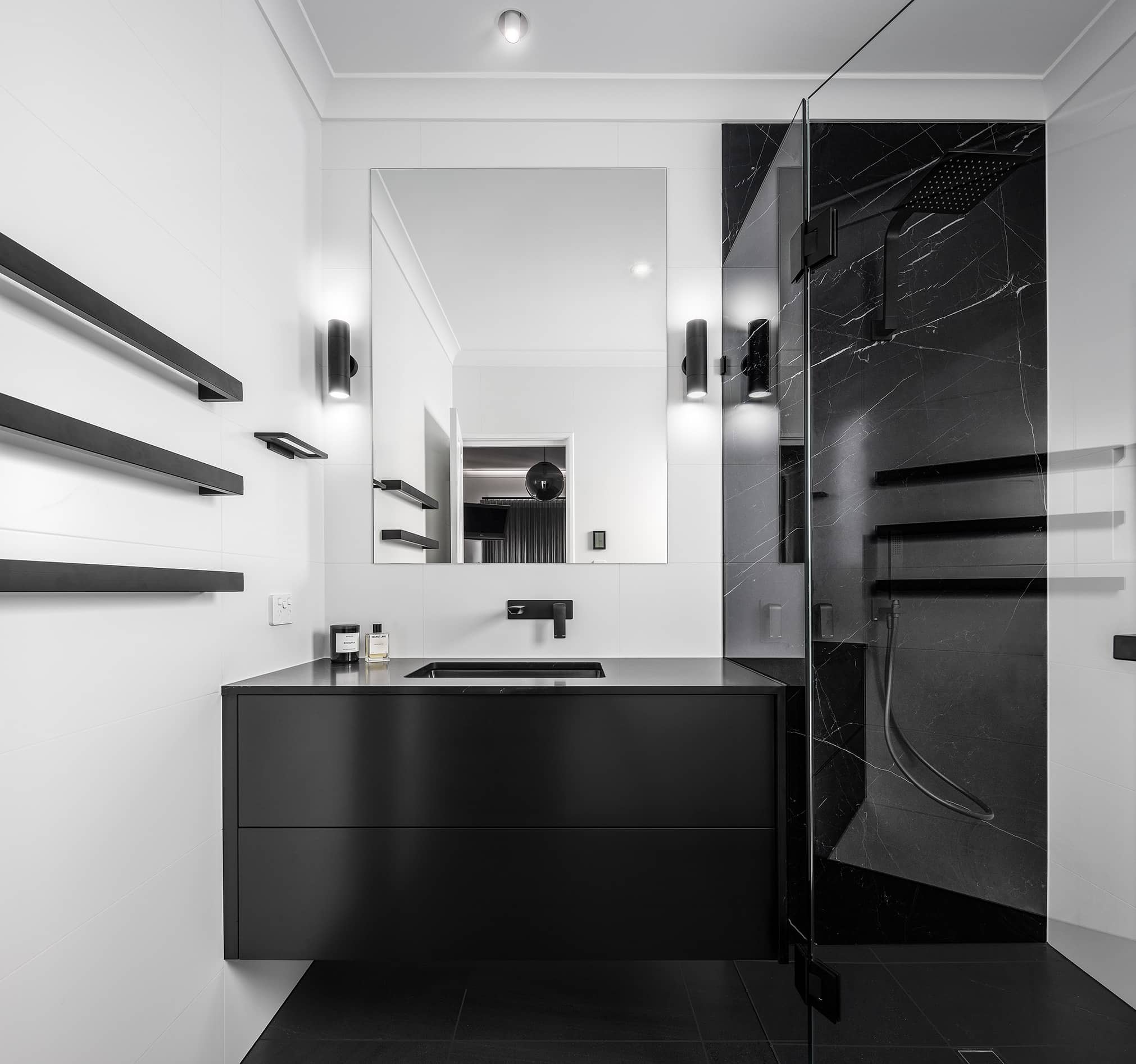 A photo of a freshly renovated bathroom, all black and white, with a shower and sink.