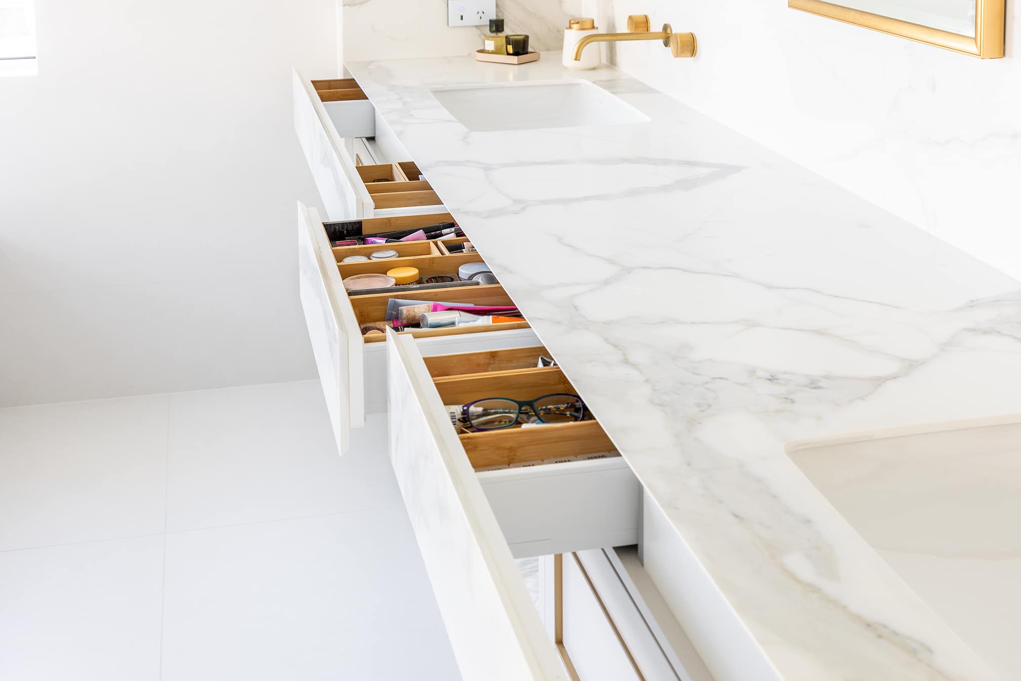 A photo of a bathroom sink, with wardrobes pulled out. There are various daily usage items in them.