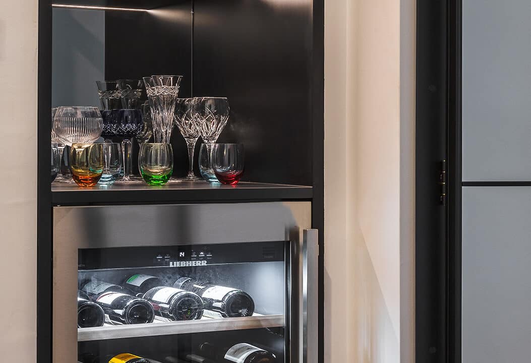 A photo of various glasses on a cooler fridge.