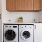 A photo of a laundry area, with a sink, washing machine and dryer.