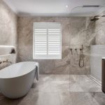 A photo of a newly renovated bathroom, with a large bathtub, shower and sink.