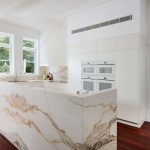 White kitchen with marble countertop.