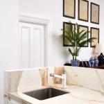 Marble countertop and sink with plants and plaques in the background