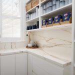 Corner of kitchen with marble counters, bowls, a toaster and a window.