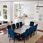 A photo of a fully renovated kitchen area with white marble decorations paired with royal blue chairs and pillows on the couches.