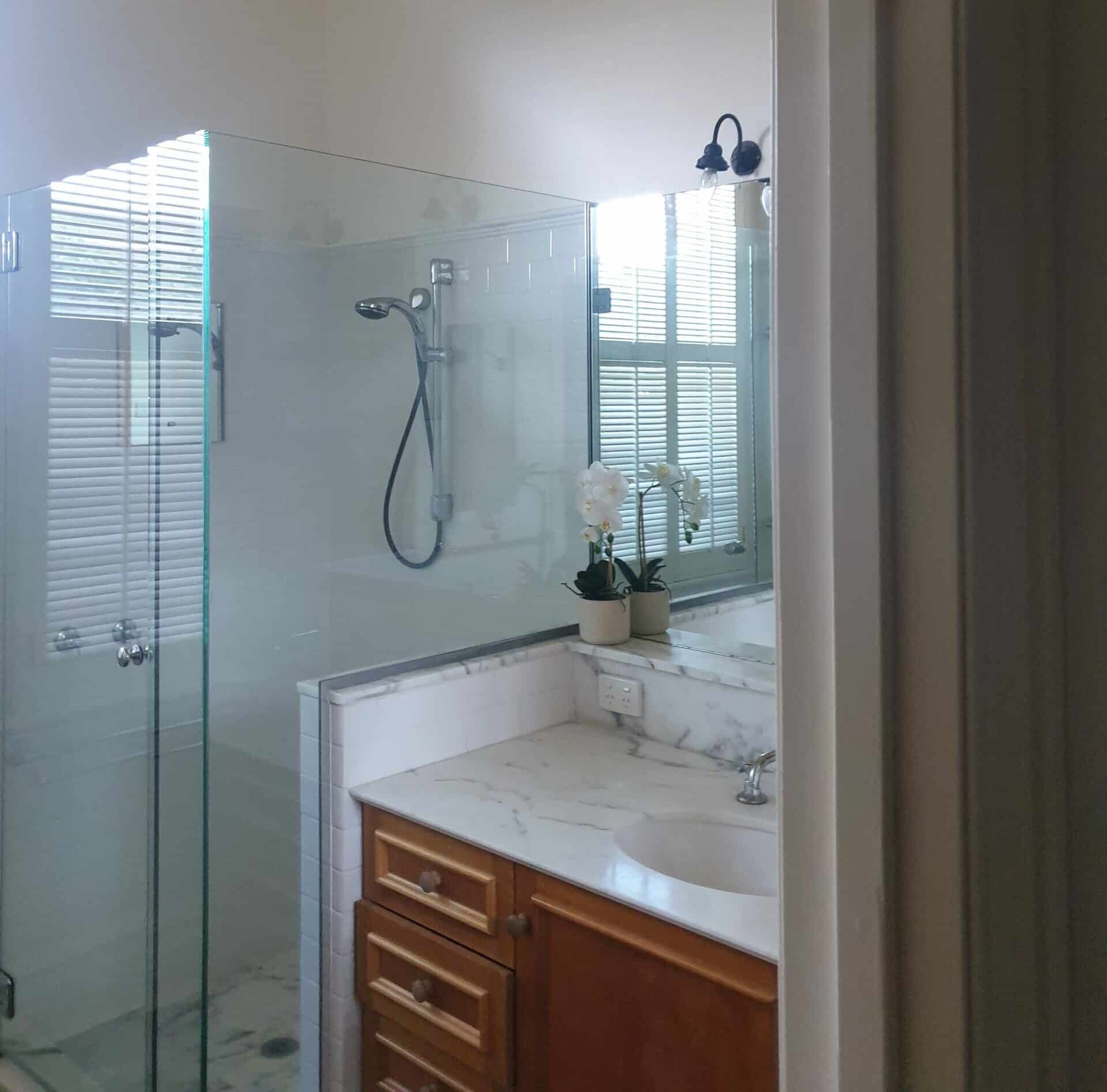 A photo of a bathroom, with a shower and sink, before being renovated by Lux Interiors.