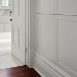 A doorway leading into white marble bathroom.