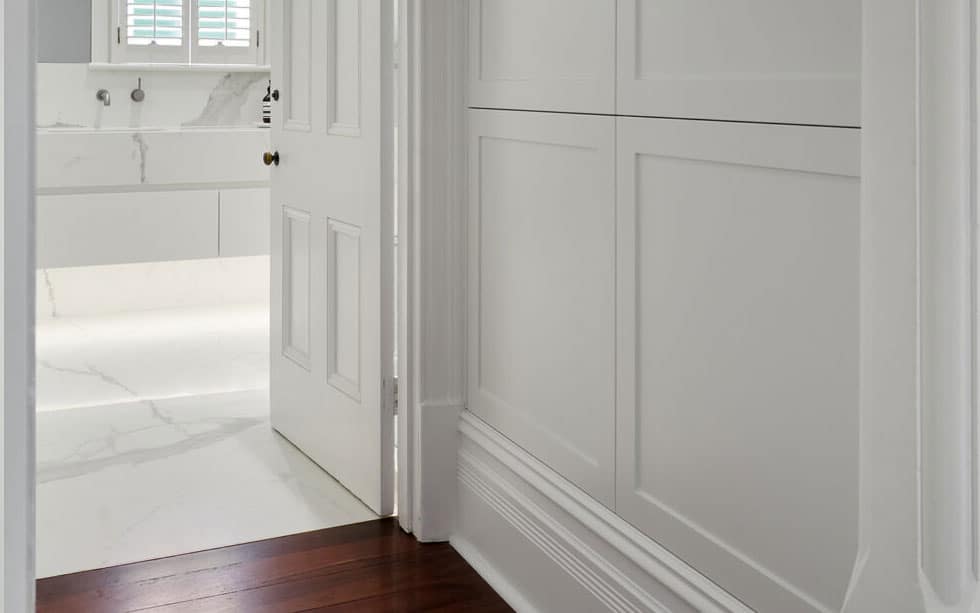 A doorway leading into white marble bathroom.