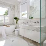 A photo of a contemporary marble look bathroom, with a bath tub, sink and shower.