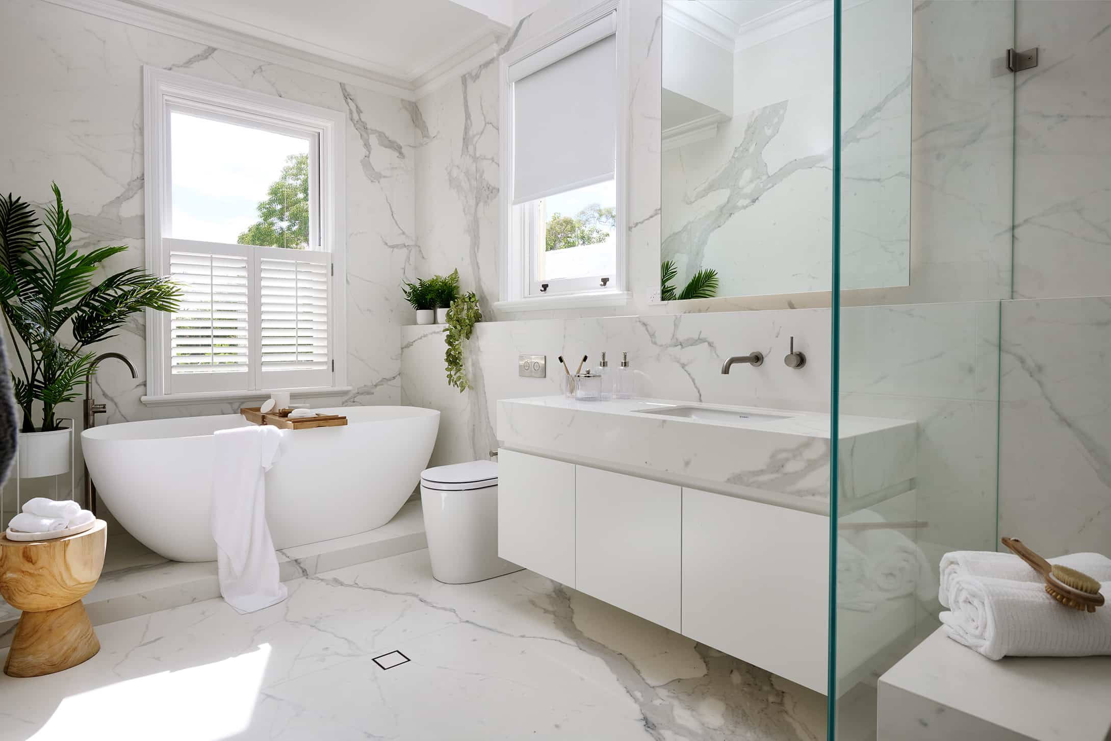 A photo of a contemporary marble look bathroom, with a bath tub, sink and shower.