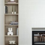 A photo of a inset wooden shelving unit, next to a fireplace.